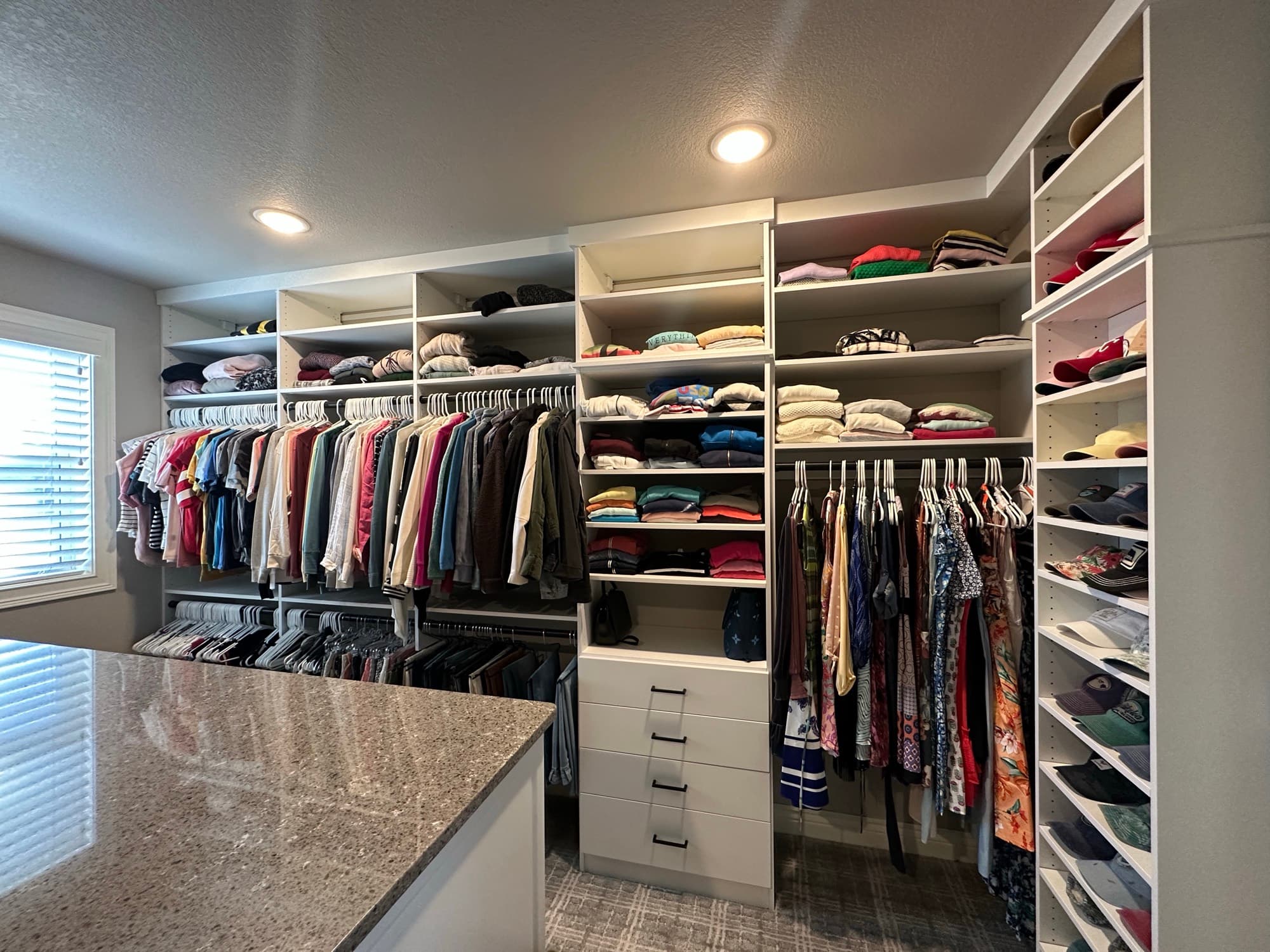 Custom walk-in closet with granite island and brass hardware